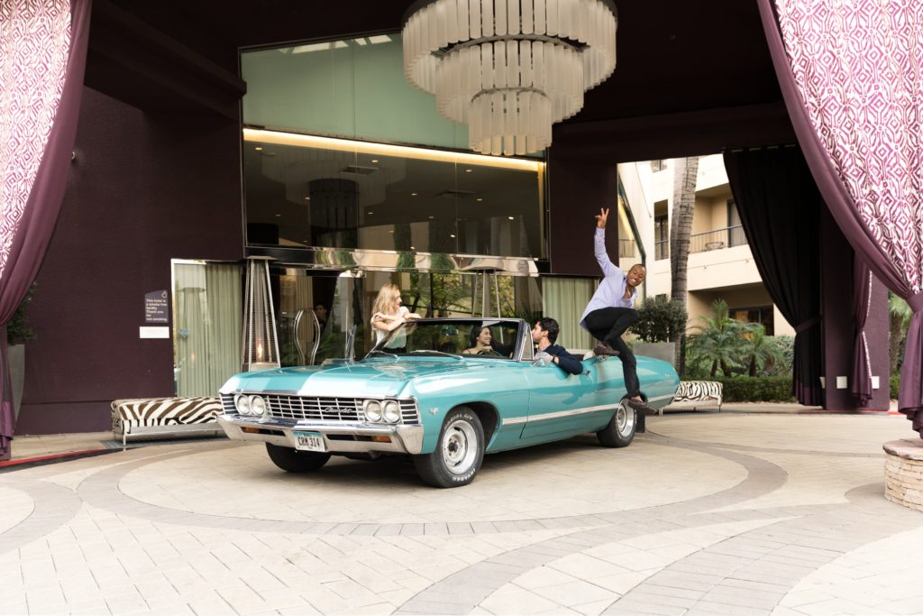 man jumping over teal car
