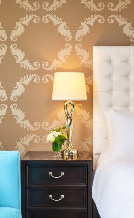 a lamp on a set of drawers between a couch and a bed