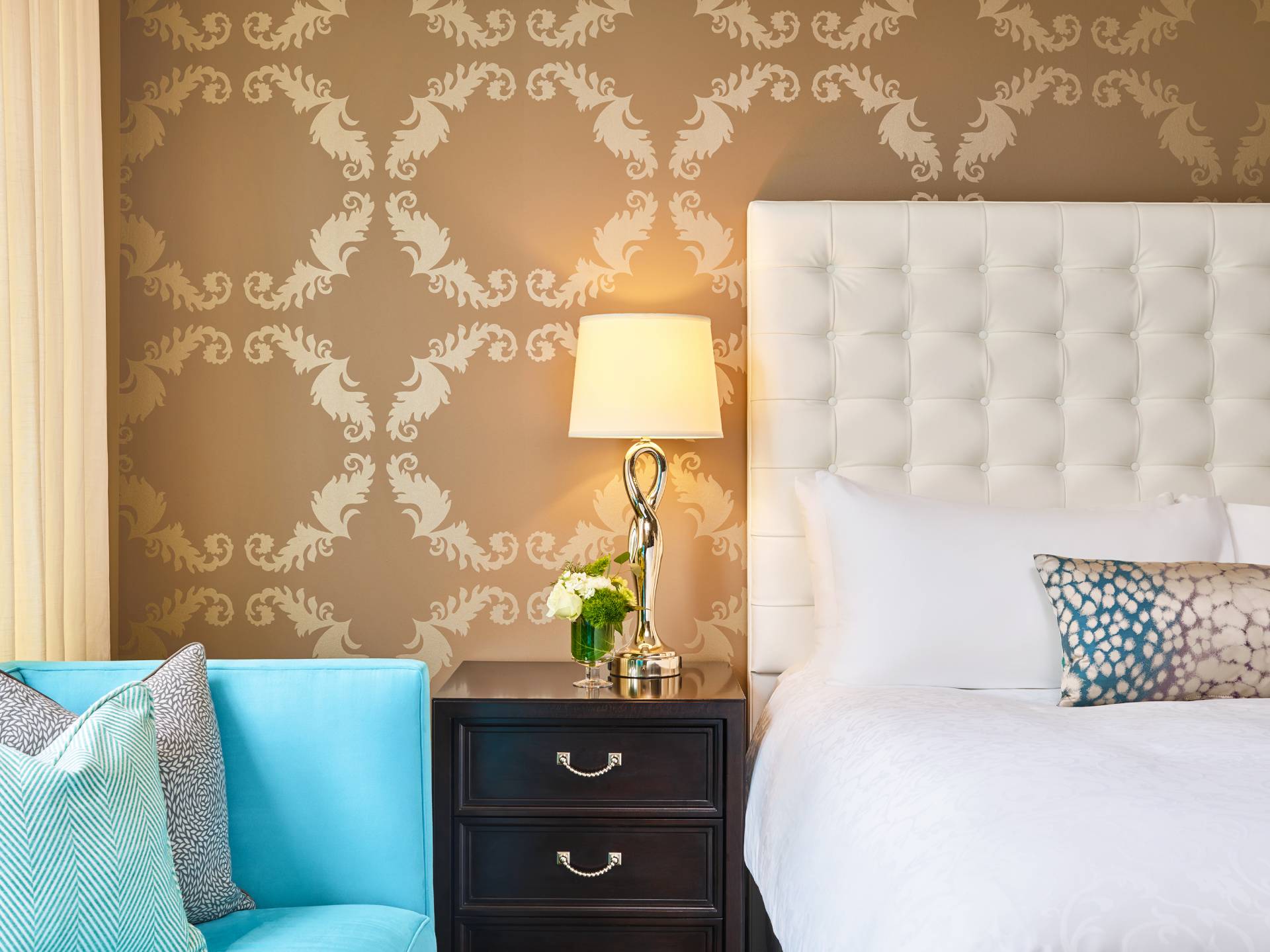 a lamp on a set of drawers between a couch and a bed