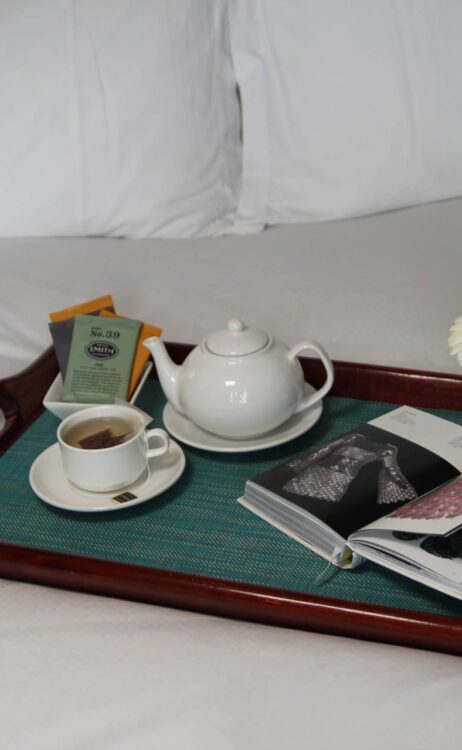 a tray with a pot of tea and a cup and saucer on a bed