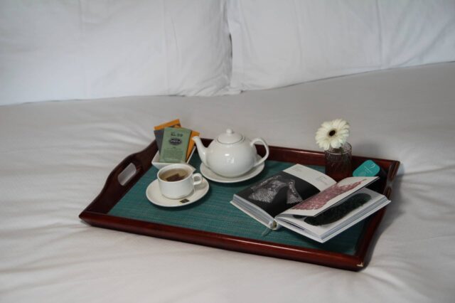 a tray with a pot of tea and a cup and saucer on a bed