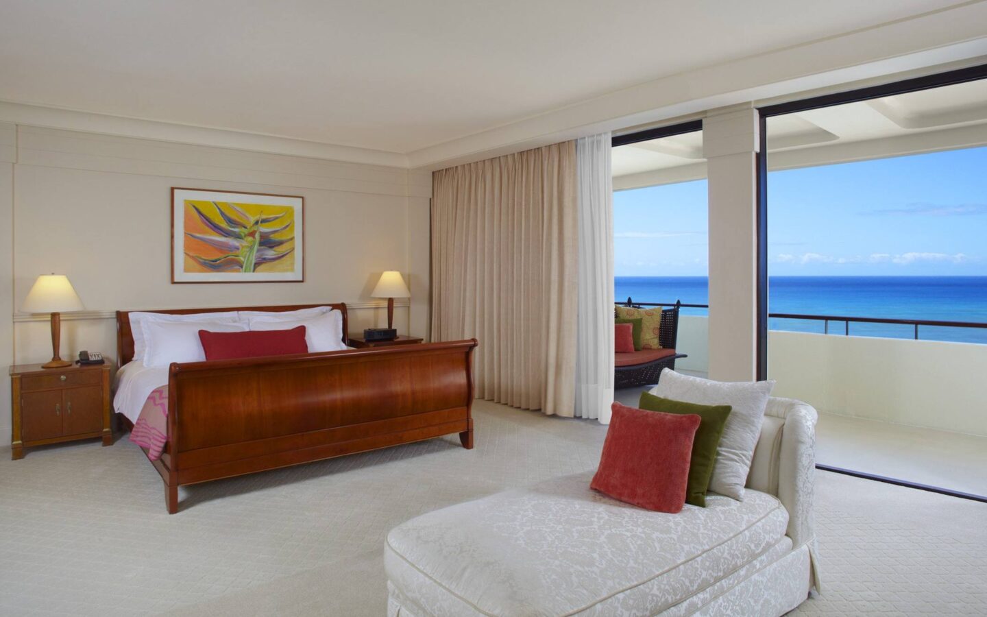 hotel suite with king bed, white day bed, and ocean view balcony