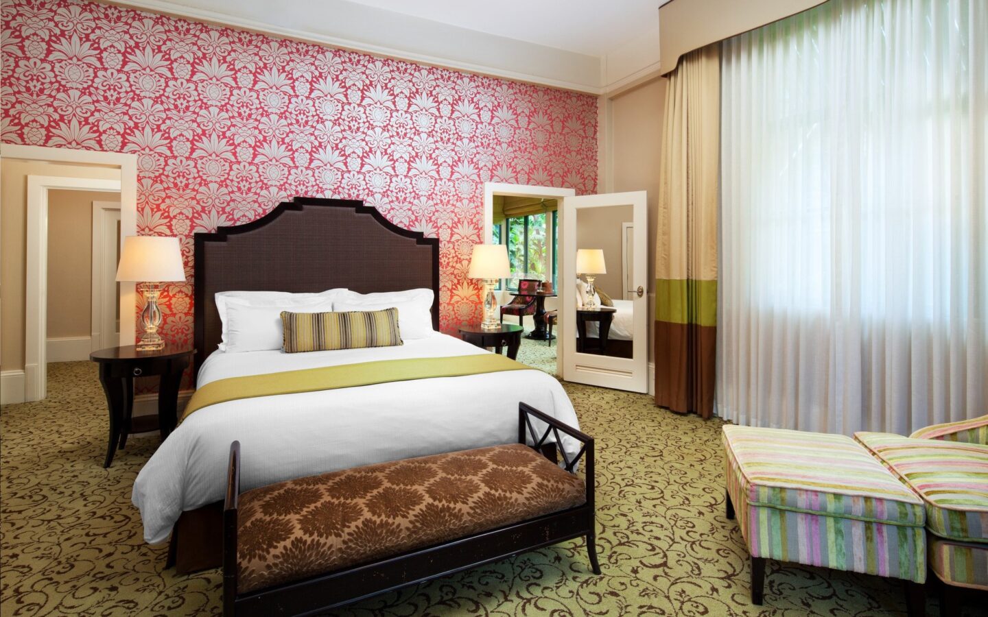 hotel room with king bed, and pink and white flowered wallpaper