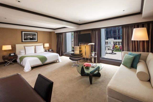 Large suite with desk, couch, table, chair, king bed, and two openings to terrace