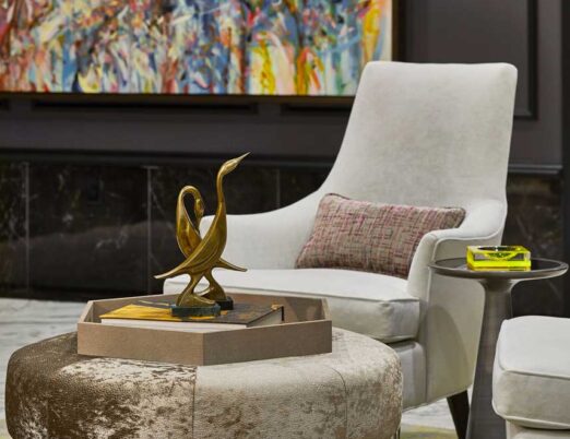 suede chairs and ottoman with a large painting on the wall behind them