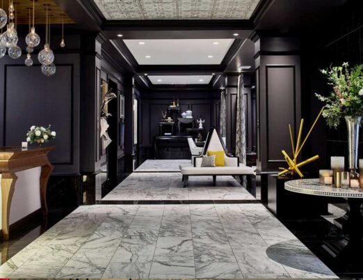 dark hotel lobby with gold accents, a white fireplace, large mirror, and large gold chandelier