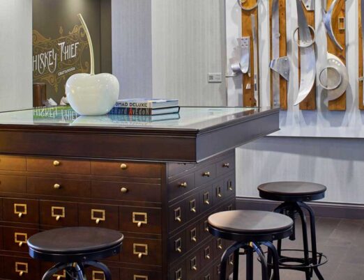 brown square table with stools surrounding it in a bright room with 3D artwork on the walls