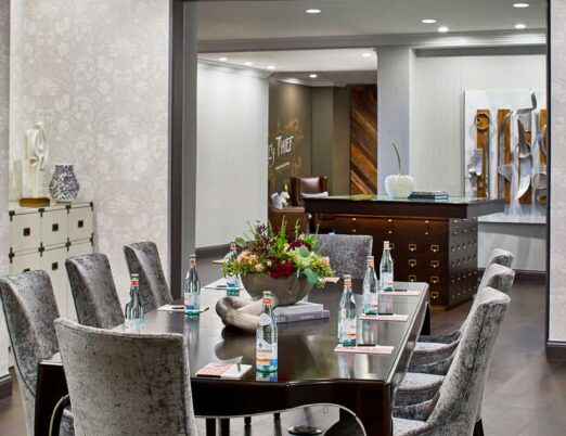luxury meeting room with a large brown table surrounded with grey suede chairs