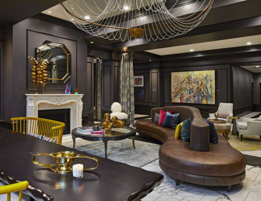 dark hotel lobby with gold accents, a white fireplace, large mirror, and large gold chandelier
