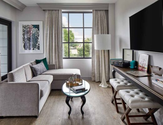 Luxury hotel living room suite with a sectional sofa, flat screen tv, and large window