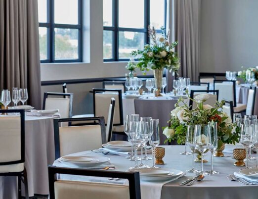 bright wedding venue room filled with tables and chairs with flower bouquet centrepieces on each table