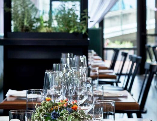 wooden tables covered with cutlery, plates, and glasses as well as a plant as a centrepiece