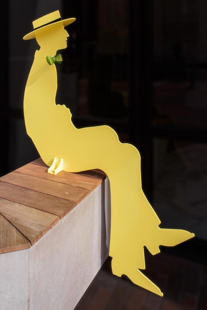 yellow artwork of a man in a hat displayed on a black wall