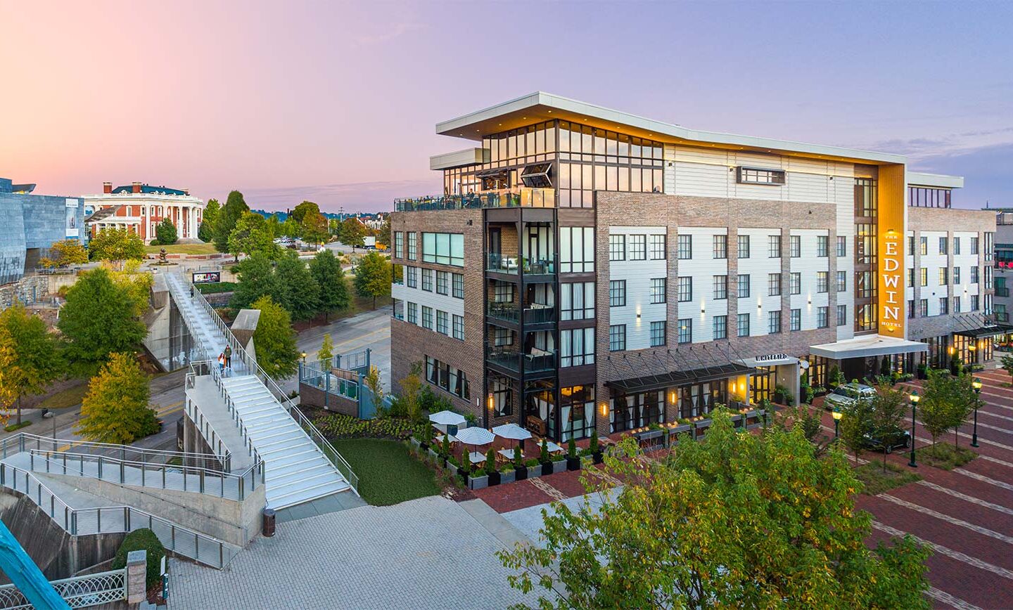 modern style hotel building surrounded by trees, streets, and walking paths for guests