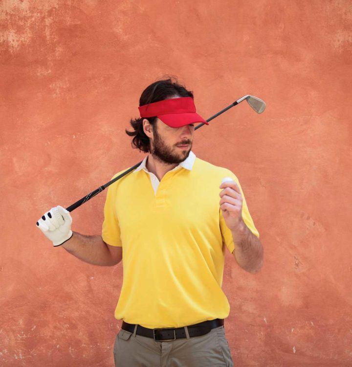 golfer in yellow and white polo shirt standing near wall