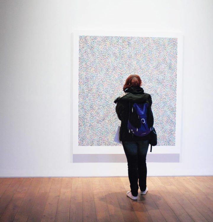 person in black jacket standing in front of art in museum