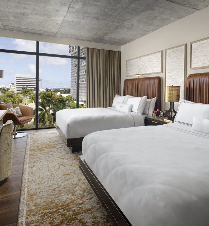 guest room with two beds next to a large window and tv
