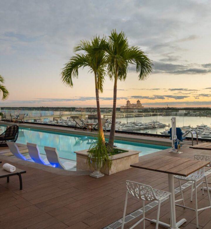 a large swimming pool with lounge chairs and palm trees