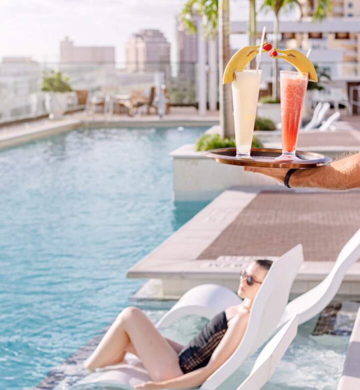 woman in white and black stripe bikini lying on white lounge chair on swimming pool during
