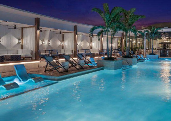 swimming pool with chairs and palm trees