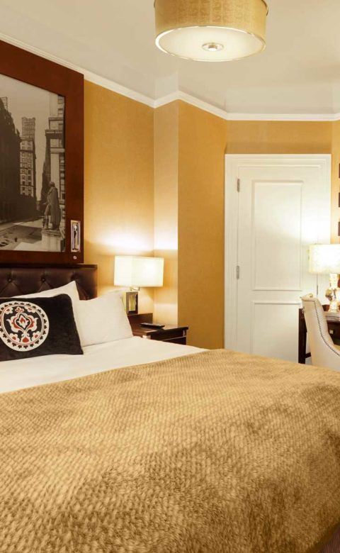 brown and white bed comforter on the king bed next to a desk space in guest room