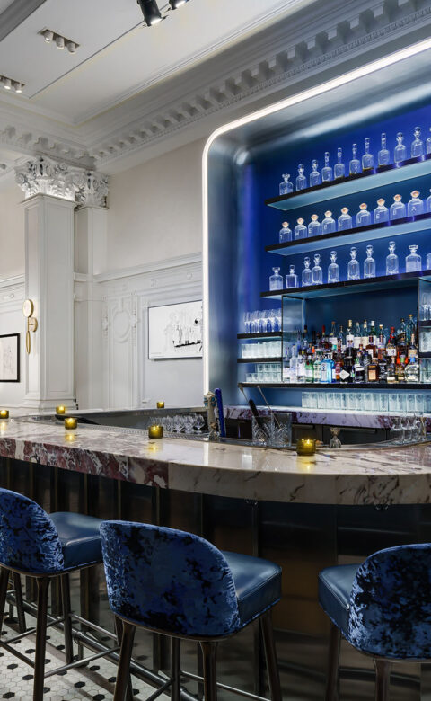 a hotel lobby bar with blue high chairs and a marble bar top