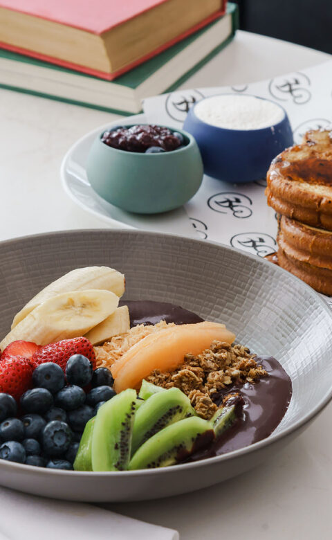 a breakfast fruit bowl with a plate of french toast