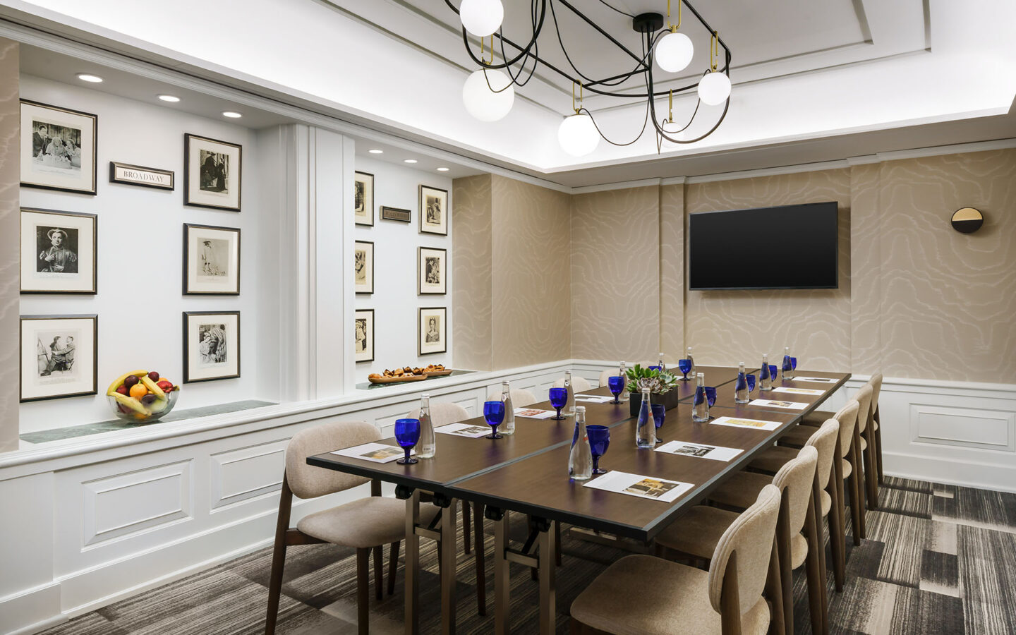 a hotel meeting room with a boardroom table and a television mounted on the wall