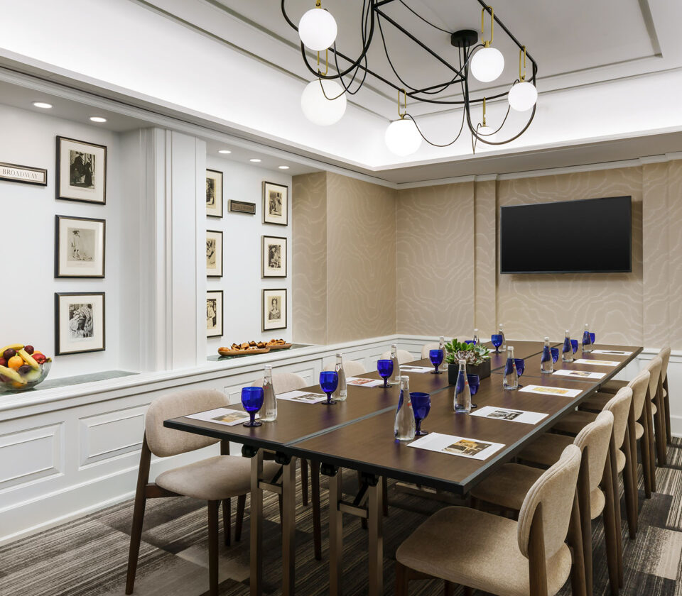 a hotel meeting room with a boardroom table and a television mounted on the wall