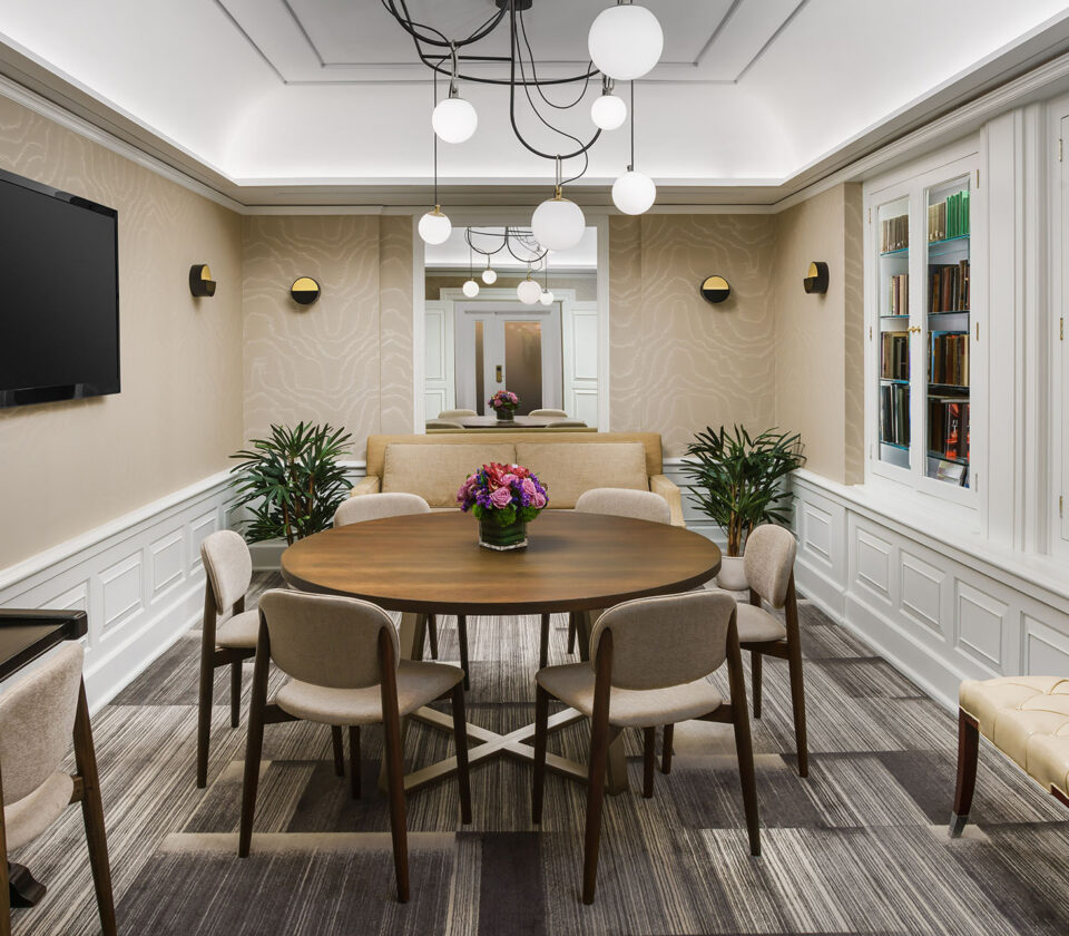 a hotel library meeting room with a round table and a TV mounted to the wall