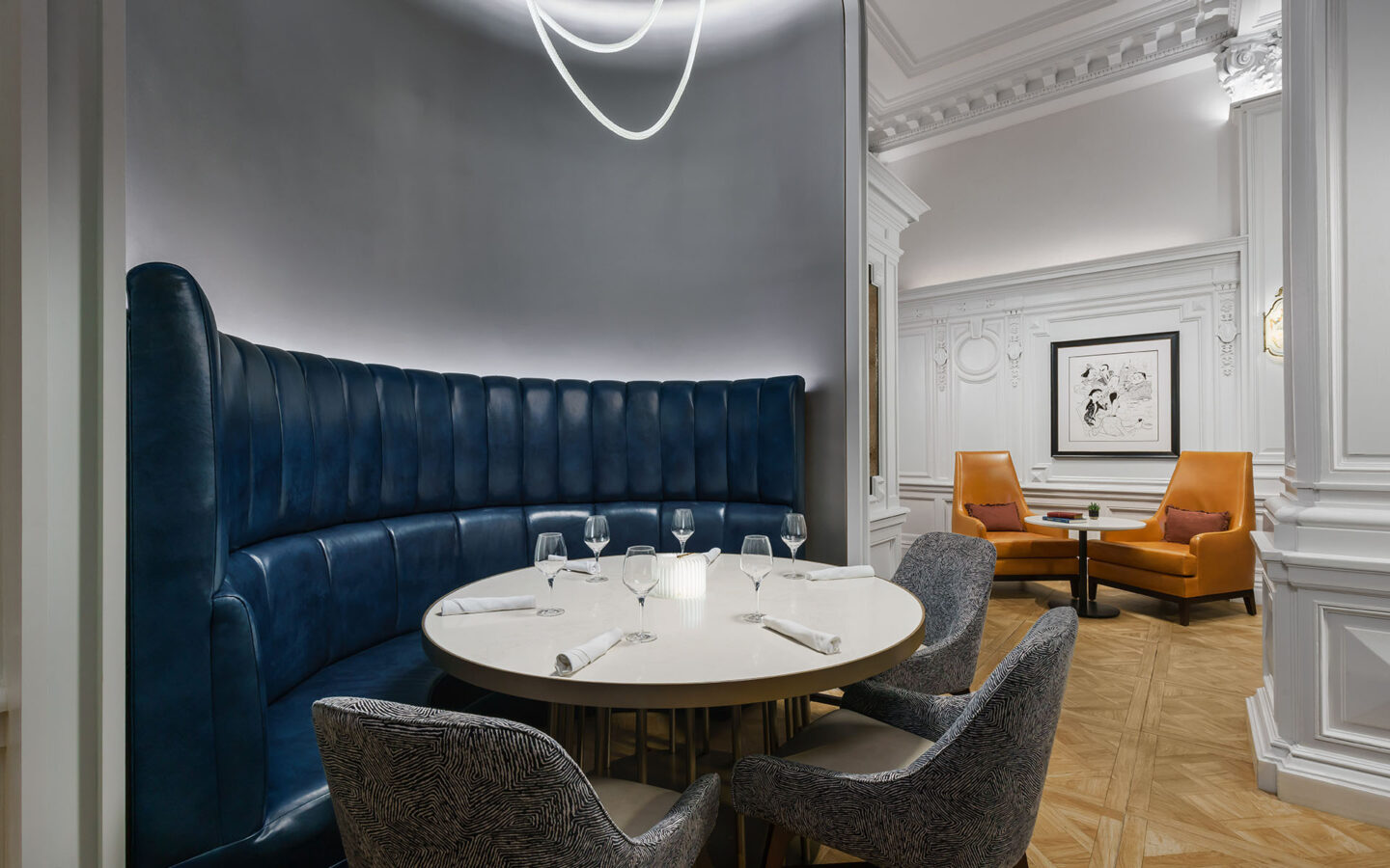 a round dining table in a hotel dining room with 3 chairs and high-backed blue leather booth seat