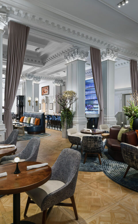 a luxury hotel piano bar dining room with small round tables and comfortable chairs and bench seating