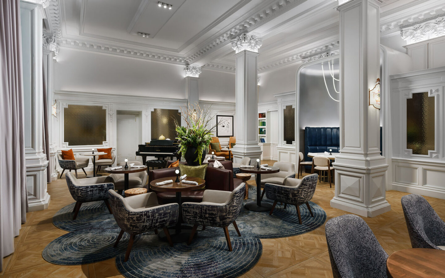 a luxury hotel piano bar dining room with small round tables and comfortable chairs