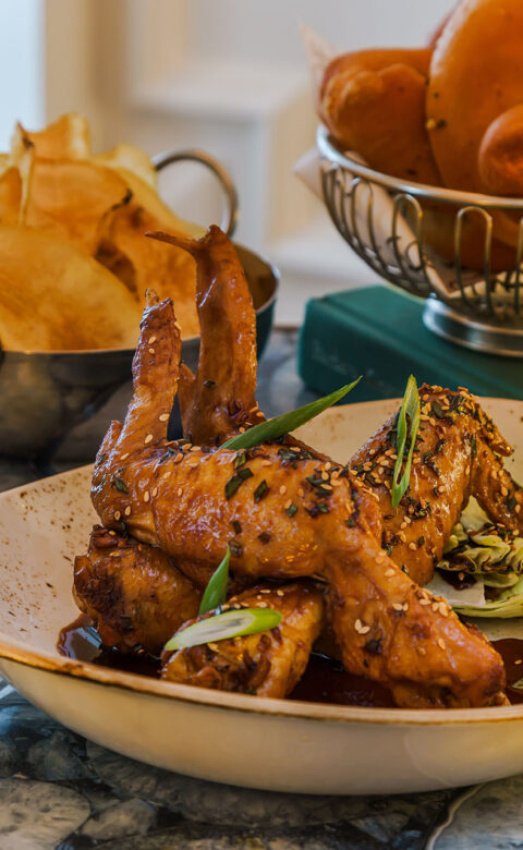 fried chicken wings topped with sauce and sesame seeds