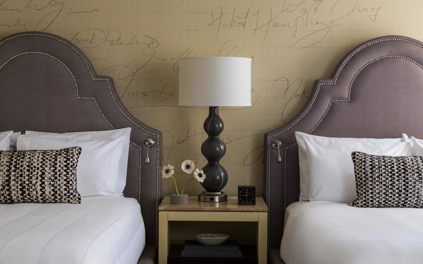 two beds with night table between them with table lamp