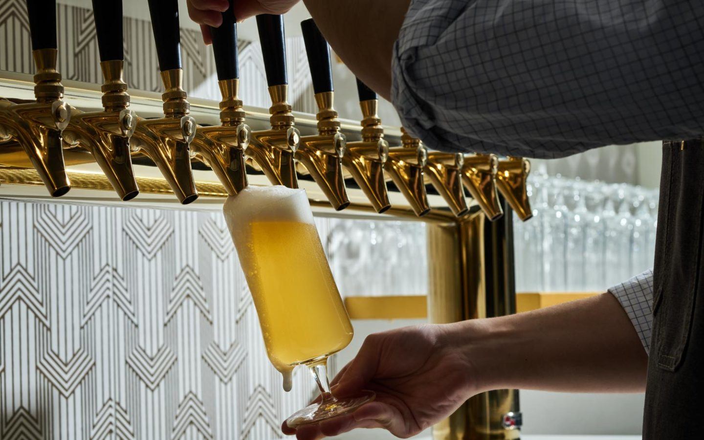 person pouring beer into a tall glass