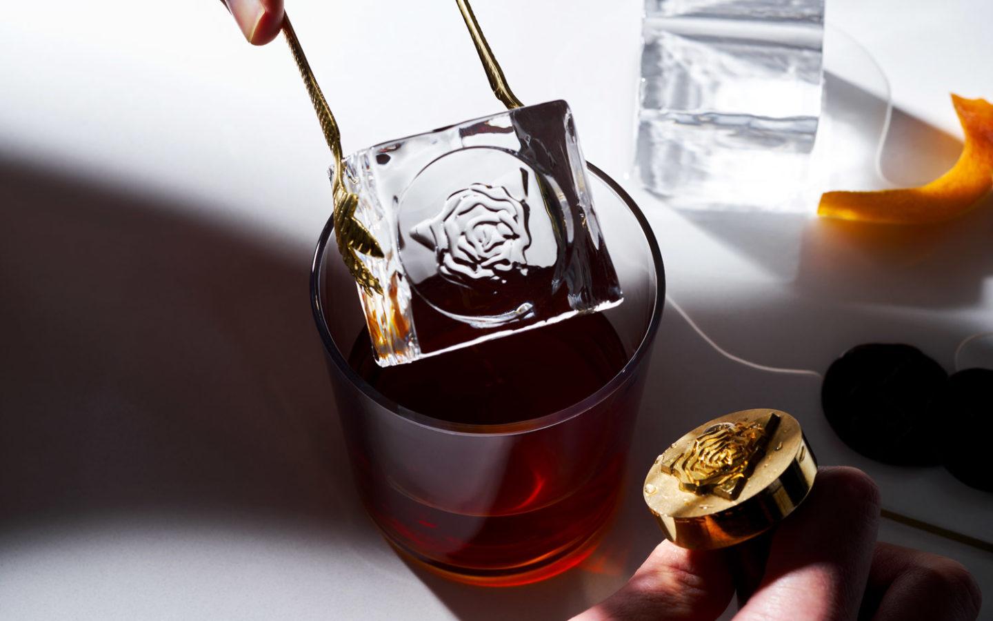 person putting an ice cube into a cocktail