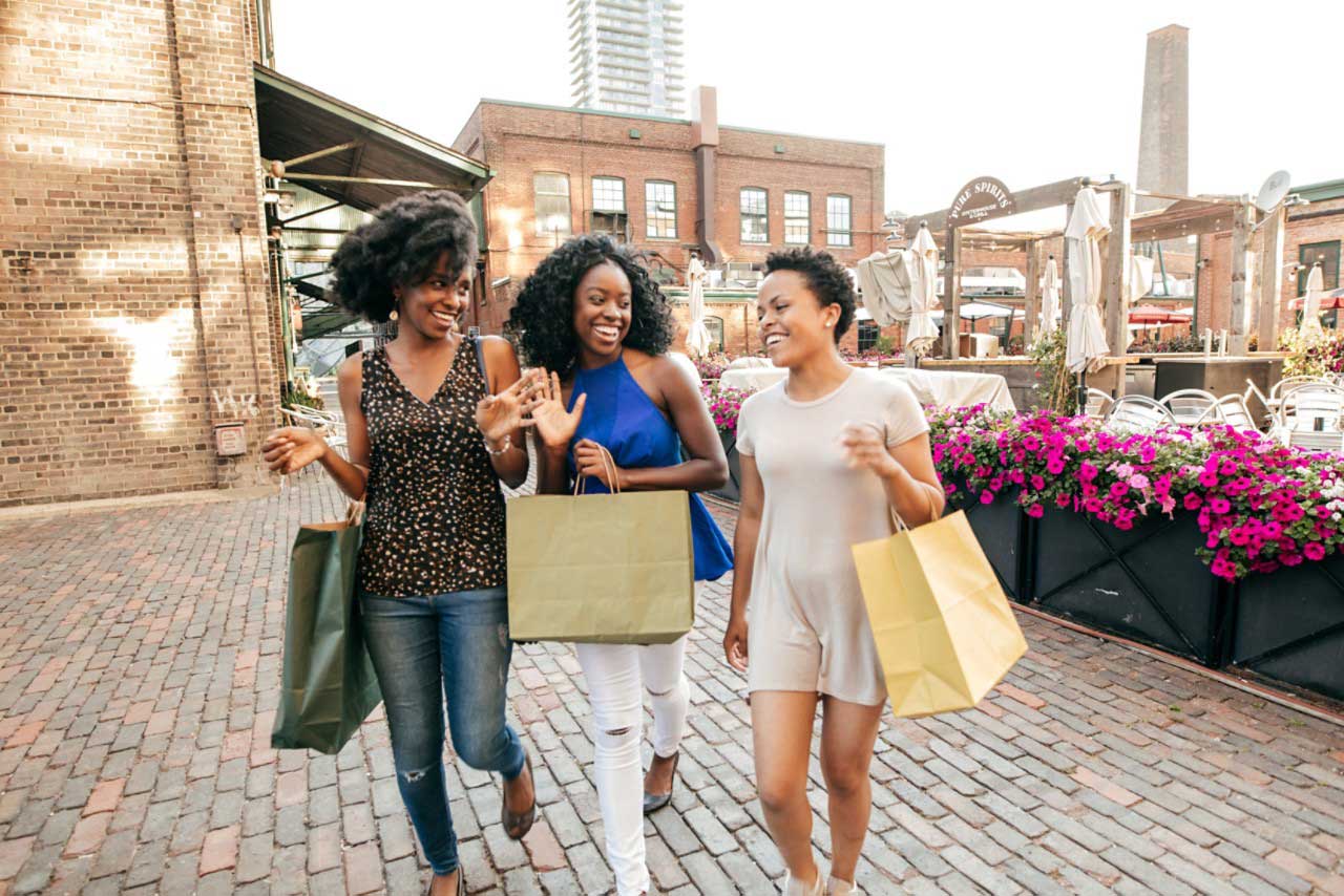 a group of women walking down a street holding shopping bags