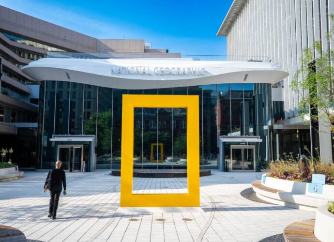 National Geographic Museum entrance with a large yellow frame sculpture in front of the glass building.