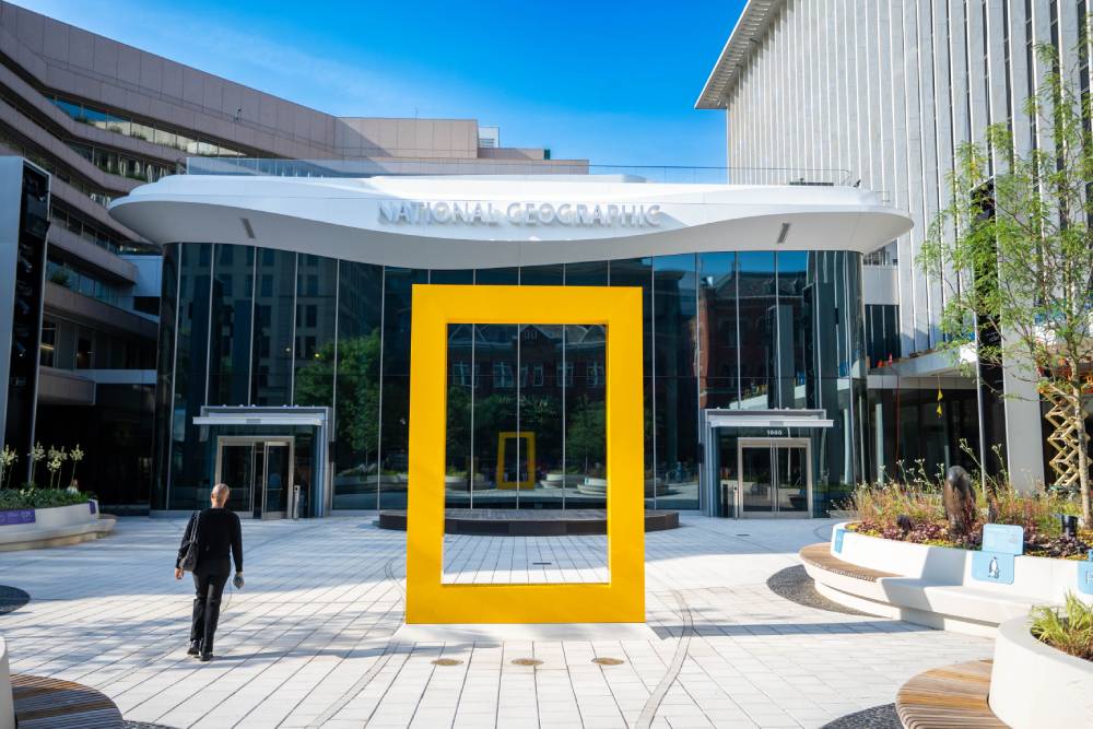 National Geographic Museum entrance with a large yellow frame sculpture in front of the glass building.