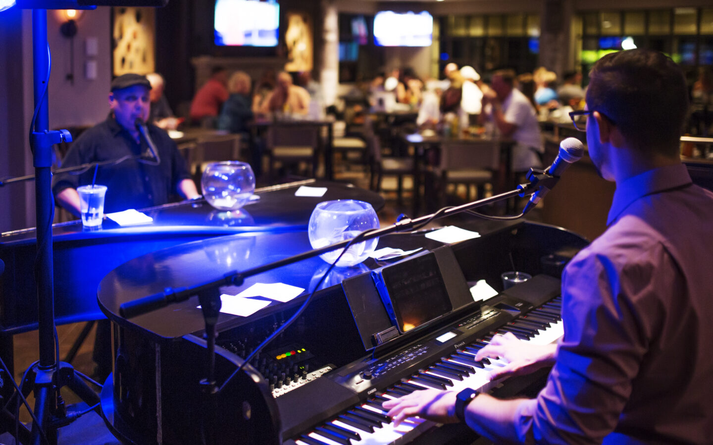 a man playing a piano in a bar and singing into the mike