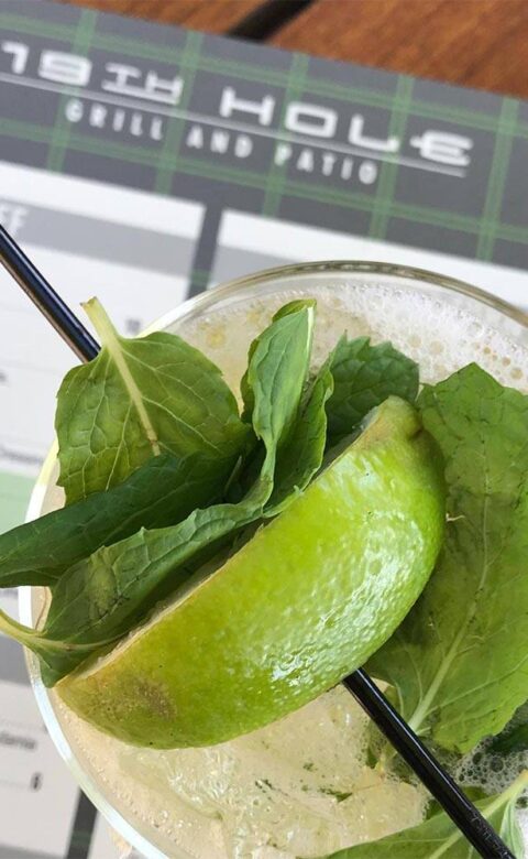 a mojito cocktail on top of a menu at 19th Hole grill and patio