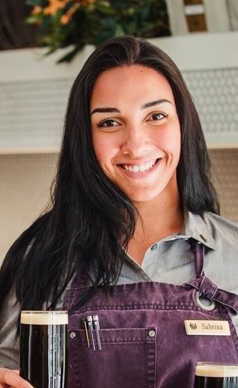 a smiling server serving dark beer at The Marketplace