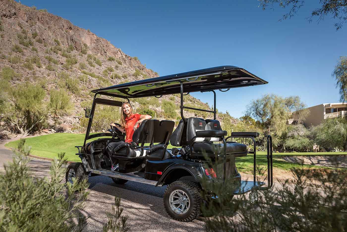 employee sits on golf cart smiling at guests
