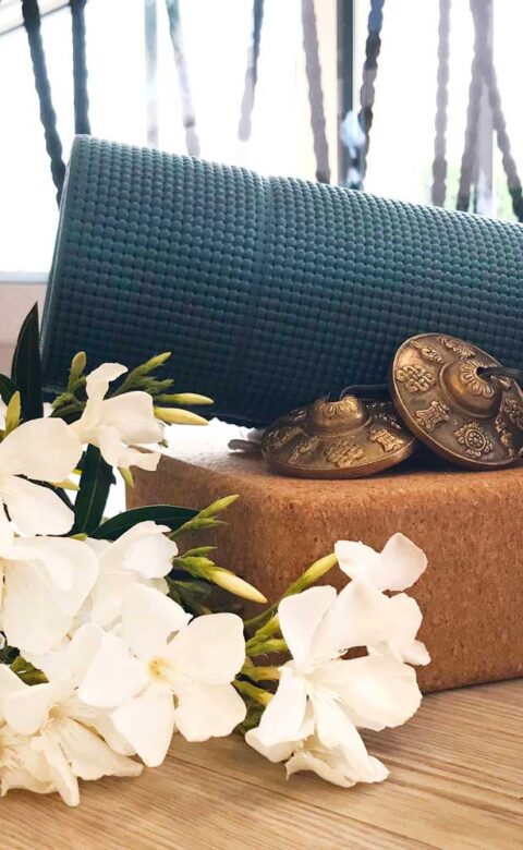 a metal water bottle sitting next to a yoga mat, some white flowers, and two lit candles