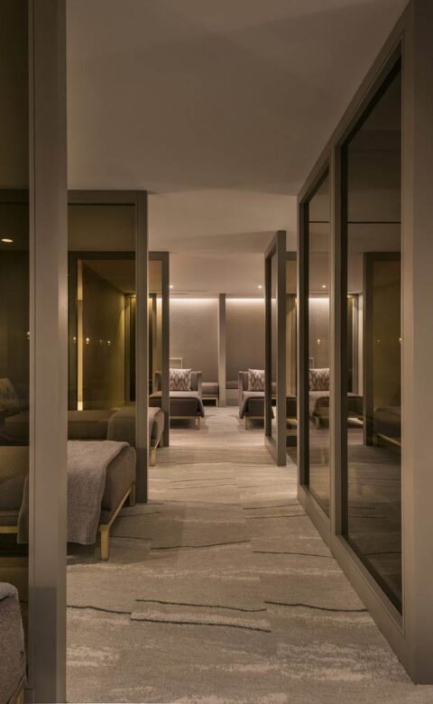 rows of daybeds, separated by glass panes, in a comfortable and dimly lit spa post-treatment room