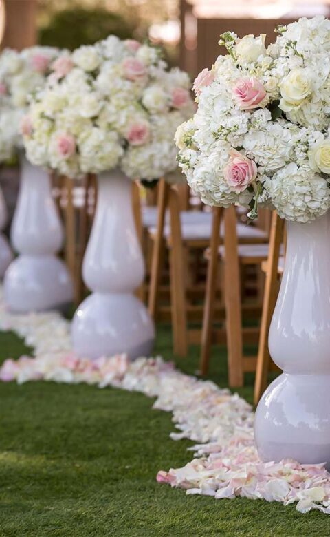 close up of flower petal covered aisle leading to flower arch set for beautiful outdoor wedding venue