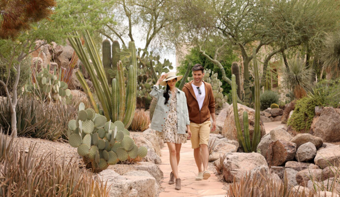 a man and a woman walking through a cactus garden