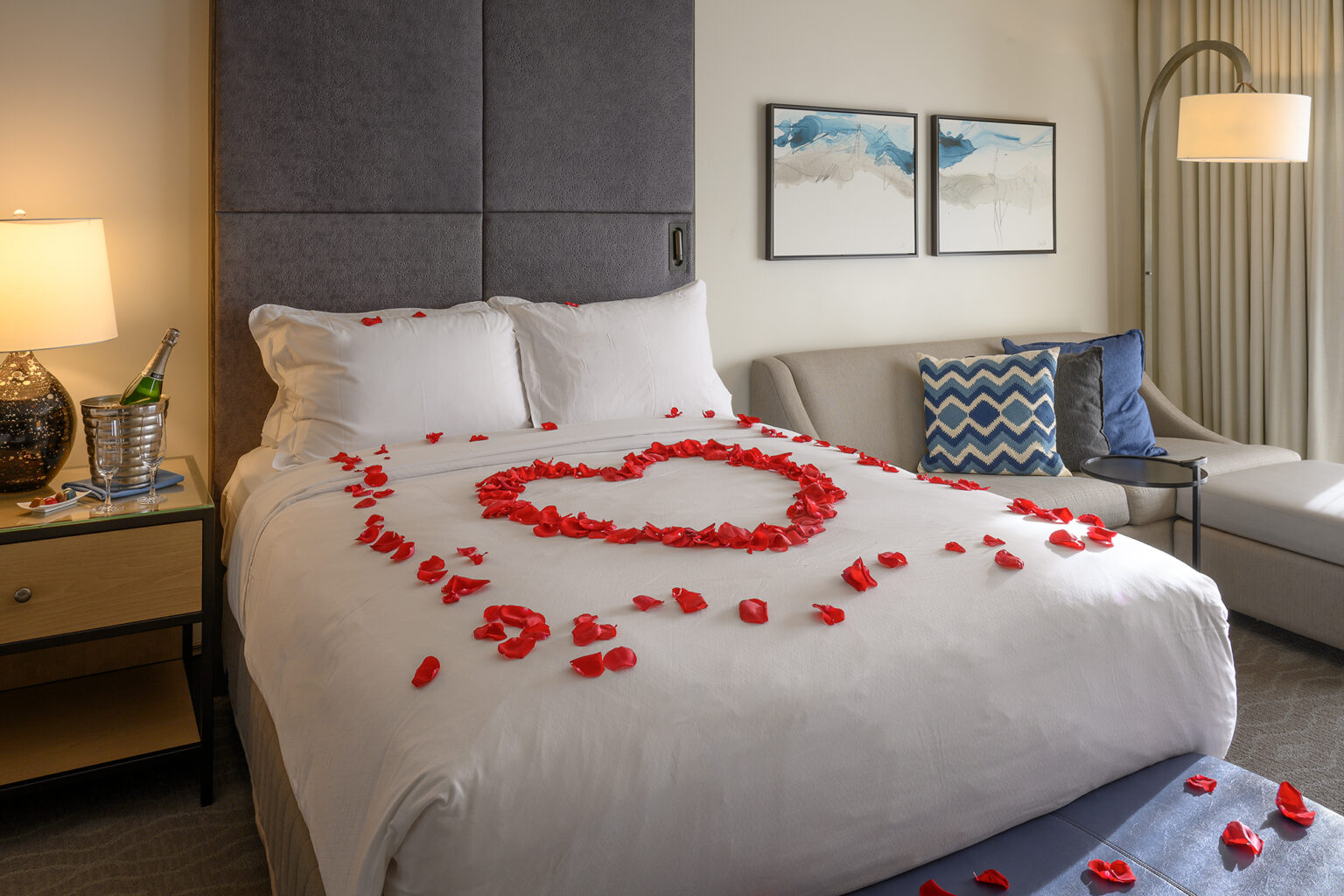a bed with rose petals in the shape of a heart on it in a hotel room