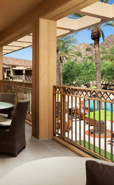 balcony with table wicker chairs and couches overlooking pool